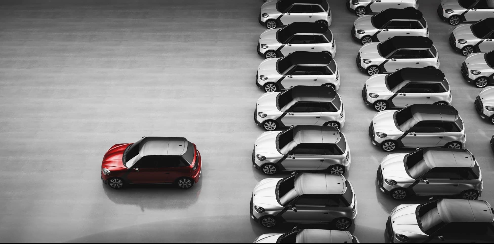 Aerial view of a fleet of identical cars with one red car standing apart